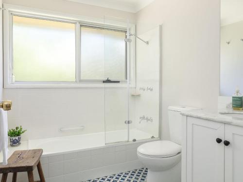 a white bathroom with a shower and a toilet at Mountain Den in Blackheath