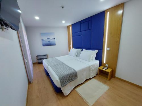 una camera con un letto bianco e una parete blu di Muralha Azibo Dreams a Santa Combinha