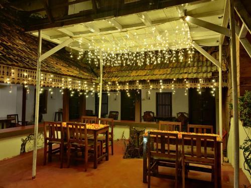 um quarto com uma mesa, cadeiras e luzes em Vrindavanam em Alappuzha