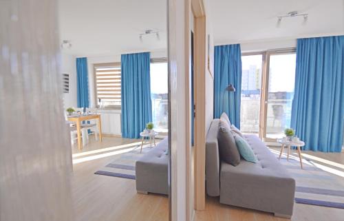 - un salon avec des rideaux bleus et un canapé dans l'établissement Apartamenty Bryza - Kwartał Róży Wiatrów, à Świnoujście