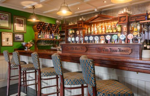 a bar with a wooden counter with bar stools at The White House in Kinsale