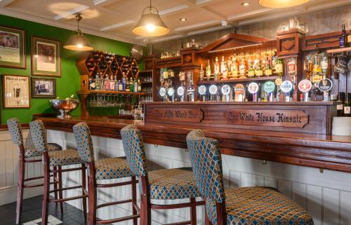 un bar con barra de madera y taburetes en The White House, en Kinsale