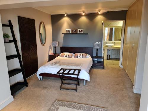a bedroom with a bed and a table and a mirror at Palm Zicht in Cape Town