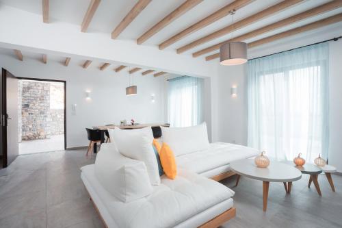 a white living room with a white couch and a table at Terra Pietra Luxury Villas & Suites in Lardos
