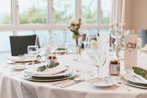 a white table with plates and wine glasses on it at Seehotel Maria Laach in Maria Laach