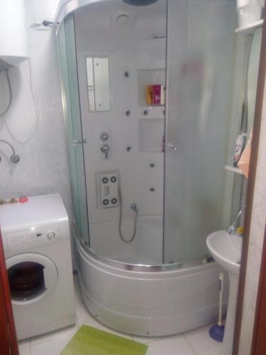 a bathroom with a shower and a washing machine at Квартира у Светы in Pizunda