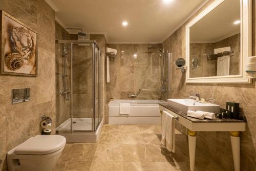 a bathroom with a toilet and a sink and a shower at Grand Pasha Hotel & Spa Kyrenia in Kérynia