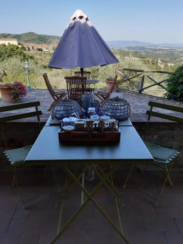 a table with chairs and an umbrella on a patio at Piccolo Relais Galletto di Marzo Spa e relax solo per due in Paciano