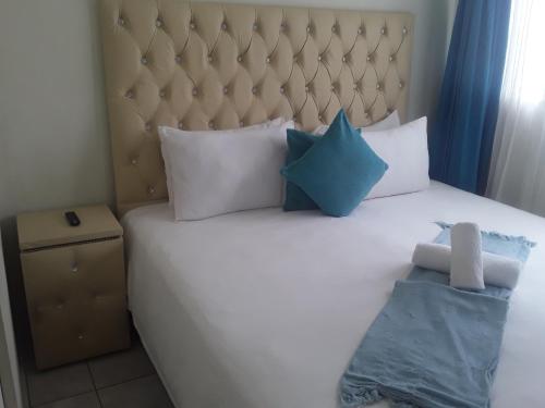 um quarto com uma grande cama branca com almofadas azuis em Kuyasa guesthouse em Mthatha