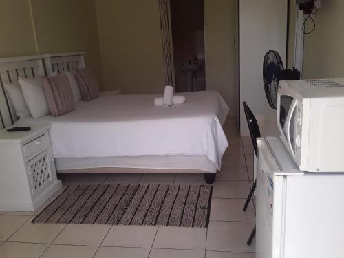 um quarto com uma cama branca e um micro-ondas em Kuyasa guesthouse em Mthatha