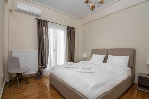 sypialnia z dużym białym łóżkiem z 2 ręcznikami w obiekcie Minimal 2 bedroom apt near the Athens Concert Hall w Atenach