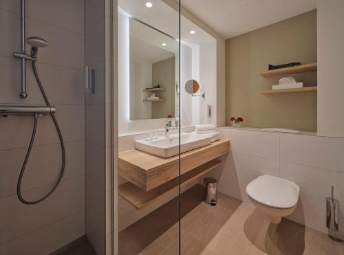 a bathroom with a sink and a toilet and a shower at Dorint Seehotel Binz-Therme in Binz