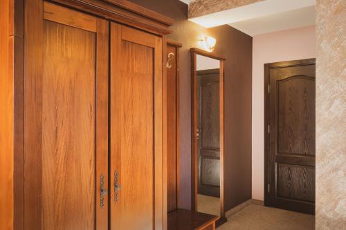 a closet with wooden cabinets and a mirror at Хотел Том и Нези Класик in Velingrad