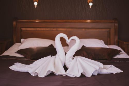 two white swans sitting on top of a bed at Хотел Том и Нези Класик in Velingrad