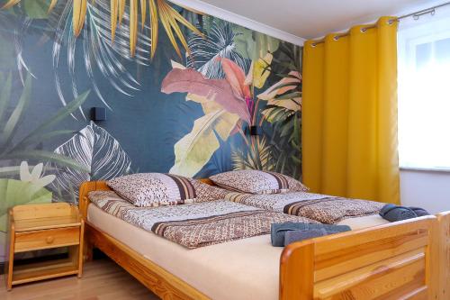 a bedroom with a bed with a tropical wallpaper at Apartamenty Częstochowa in Częstochowa
