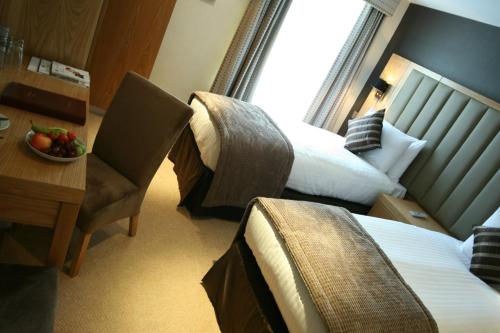 ロンドンにあるロード ジム ホテル ロンドン ビクトリアのベッド2台、テーブル(フルーツボウル付)が備わる客室です。