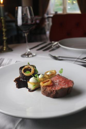 a white plate with a piece of meat and a glass of wine at Tower Hotel in Lincoln