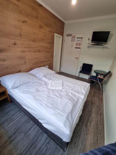 - une chambre avec un grand lit blanc et un mur en bois dans l'établissement Puschkin Rooms, à Berlin