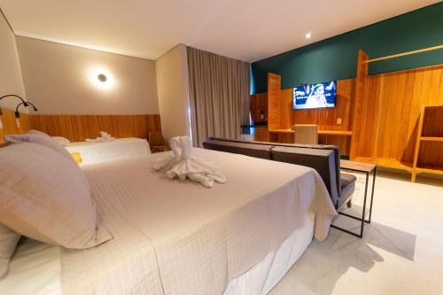 a hotel room with a white bed and a television at Hotel da Praça in Bonito