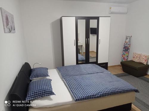 a bedroom with a bed with blue pillows and a mirror at DALMAR Apartman in Bihać