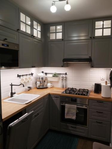 a kitchen with gray cabinets and a stove top oven at Apartament IZBA - mieszkanie na doby GDAŃSK in Gdańsk