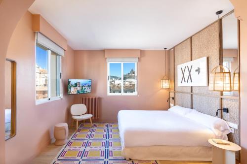 a bedroom with a white bed and two windows at La Bella Granada in Granada