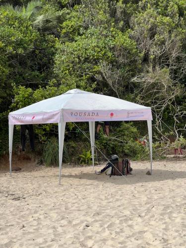 a white tent sitting on the sand on a beach at Pousada Rosa Center in Praia do Rosa