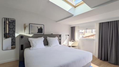 - une chambre avec un grand lit blanc et une lucarne dans l'établissement Maison Juste, à Marseille