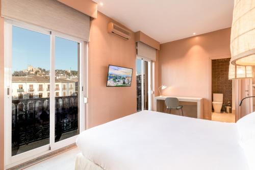 a bedroom with a bed and a large window at La Bella Granada in Granada