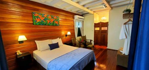 een slaapkamer met een bed en een houten muur bij Prins Hendrik Suites in Paramaribo