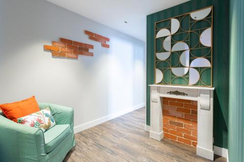 a living room with a green chair and a fireplace at Fly Rooms Madrid Airport in Madrid