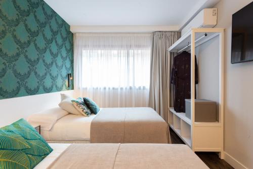 a hotel room with two beds and a window at Fly Rooms Madrid Airport in Madrid