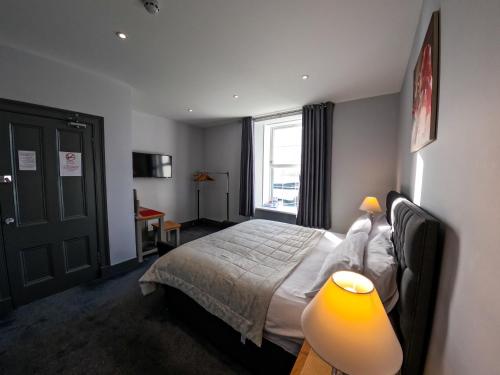 1 dormitorio con 1 cama con lámpara y ventana en Maryfield House Hotel en Lerwick