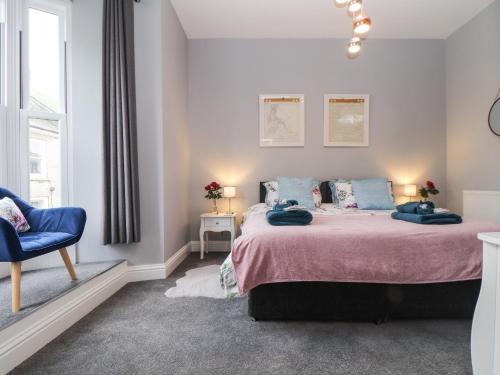 a bedroom with a large bed and a blue chair at Baker Chambers in Camborne