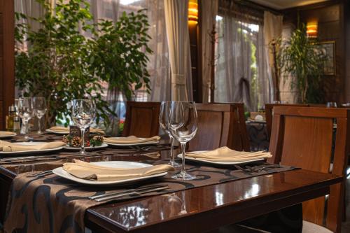 a table with plates and wine glasses on it at Хотел Том и Нези Класик in Velingrad