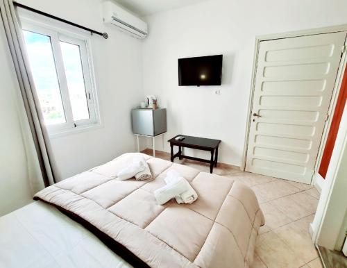 a white bedroom with a large bed and a window at Avra Rooms in Karpathos Town