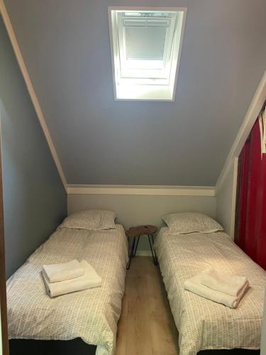 two twin beds in a room with a window at Tiny-House van zeecontainers bij het bos in Oranjewoud