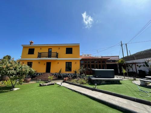 una casa amarilla con césped delante en Villa Tijuana - Jacuzzi, Playa y Naturaleza en Gran Canaria, en Las Palmas de Gran Canaria