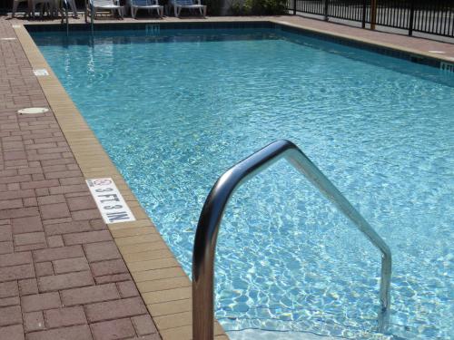 a swimming pool with a metal handrail in a building at Travelodge by Wyndham Orlando at Heart of International Drive in Orlando