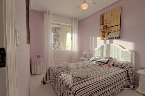 een witte slaapkamer met een bed met een gestreepte deken bij 058 - Parque y Playa 002 - comfortHOLIDAYS in Santa Pola