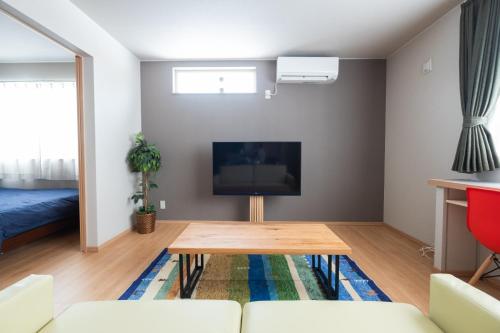 a living room with a table and a tv at Stay In Biei in Biei