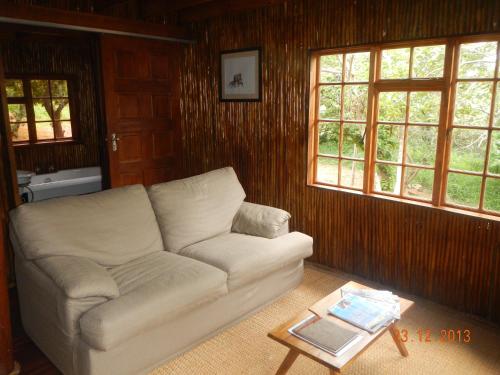 a living room with a white couch and two windows at Amafu Forest Lodge in Hoedspruit