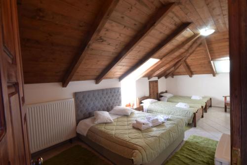 a bedroom with two beds in a room with wooden ceilings at Mountain House in Karpenisi