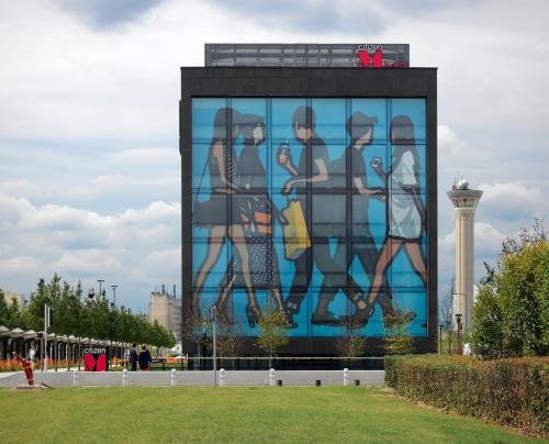 un grand bâtiment avec une fresque murale représentant des gens. dans l'établissement citizenM Paris Charles de Gaulle Airport, à Roissy-en-France