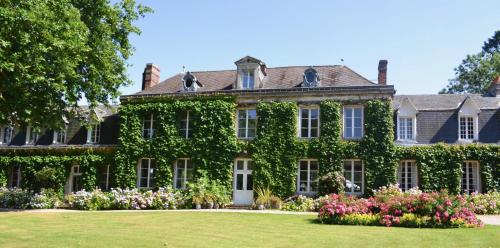 ein mit Efeu bedecktes Haus mit Blumen im Hof in der Unterkunft Château d'Harcelaines in Maisnières