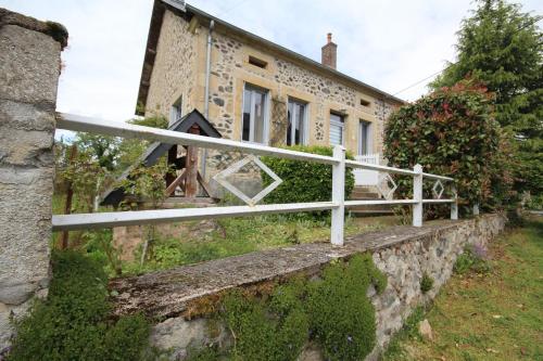 a white fence in front of a stone house at Gîte du Verger in Onlay