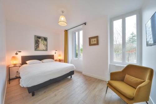 a bedroom with a bed and a chair and windows at La Maison d'Hera in Vierzon