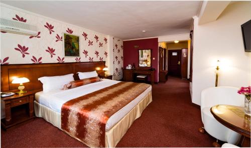 a hotel room with a large bed and a desk at Hotel Palas in Kazanlŭk