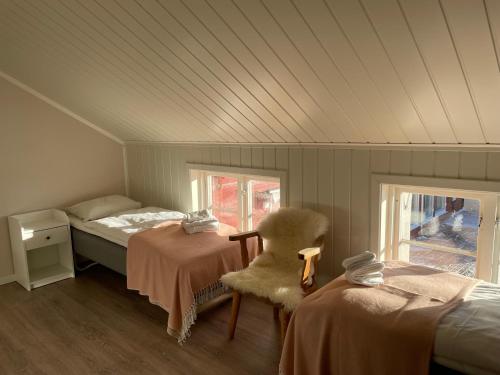 a bedroom with two beds and a chair and a window at Lillehammer Fjellstue og Hytteutleie in Nordseter