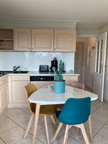 une cuisine avec une table, des chaises et une plante en pot dans l'établissement La Timonerie - Escapade 33, vue mer et esplanade classé 3 étoiles, à Fort-Mahon-Plage